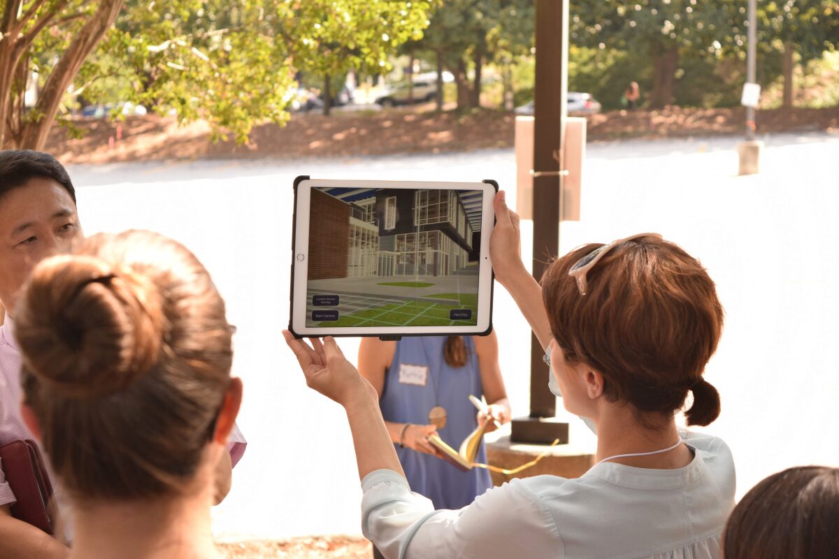 woman holding up display screen as others look on