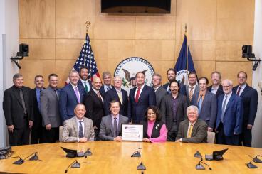 Representatives from Natura Resources, the Zachry Group, Abilene Christian University, The University of Texas at Austin, Texas A&M University, and the Georgia Institute of Technology receive the issued Construction Permit at the Nuclear Regulatory Commission. (Image credit – Natura Resources LLC)